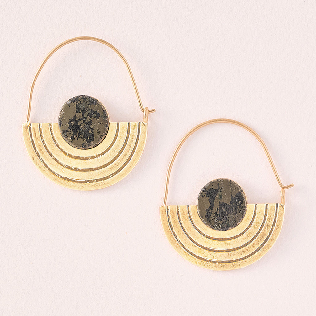 The Stone Orbit Earring Pyrite Gold by Scout Jewelry features hypoallergenic, 14K gold-dipped earrings with semi-circular layered designs and a round pyrite stone at the top, plus a thin curved wire for comfort.