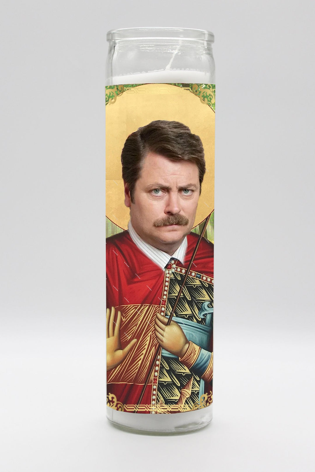 Introducing the Ron Swanson Candle by BOBBYK BOUTIQUE: A stylish, tall, unscented candle that portrays a man with a mustache in a red and gold robe, holding a staff against a gold halo backdrop, reminiscent of religious iconography. Set against a plain white background.