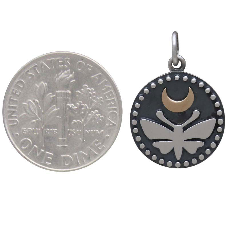 A US dime sits next to Nina Designs’ Sterling Silver Moth Charm, featuring a luna moth with a bronze moon and dot accents along the round pendant’s edge.