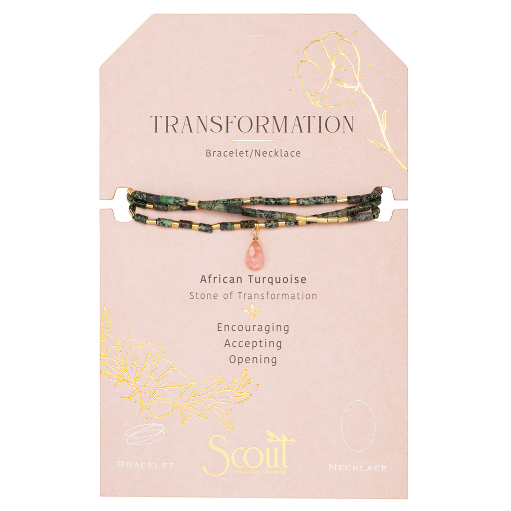 The Scout Jewelry Transformation African Turq Gold Teardrop Wrap is a bracelet/necklace with green and gold beads, a pink charm, on a "Transformation" card featuring African turquoise and floral gold accents.
