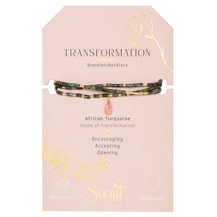 The Scout Jewelry Transformation African Turq Gold Teardrop Wrap is a bracelet/necklace with green and gold beads, a pink charm, on a "Transformation" card featuring African turquoise and floral gold accents.