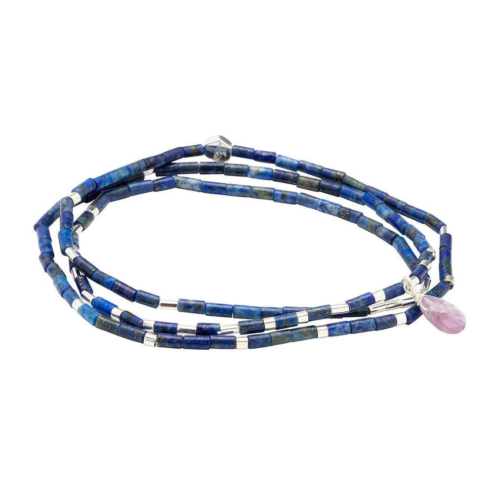 The Scout Jewelry Clarity Lapis Silver Teardrop Wrap is a bracelet with small blue lapis beads, silver accents, and a single pink teardrop charm.