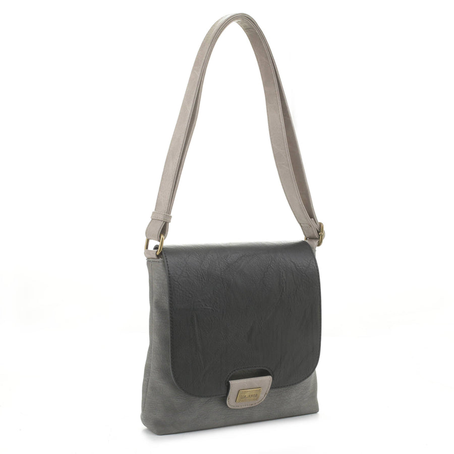 The Liz Soto Handbags Amy Crossbody - Black is a stylish two-tone shoulder bag made from plush vegan leather, featuring a light gray body, dark gray flap, adjustable strap, and a small rectangular metal label on the front.