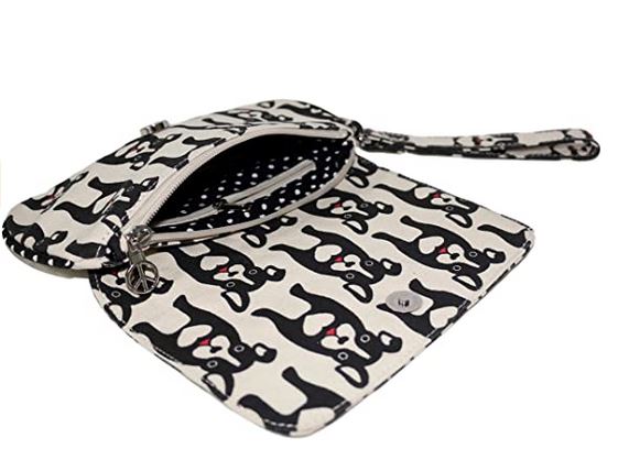 The Bungalow 360 Large Wristlet features a black and white dog print on cotton canvas, a matching wrist strap, an open flap, and a zippered polka dot interior. This vegan bag combines playful style with practical design.