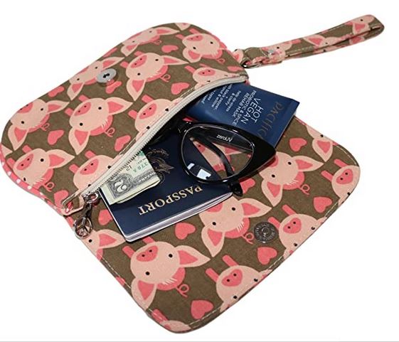 The Bungalow 360 Large Wristlet Pig features a cute pink pig pattern, brown eco-friendly material, and snap closure. Open it to reveal space for your passport, cash, and sunglasses—perfect for travel essentials.