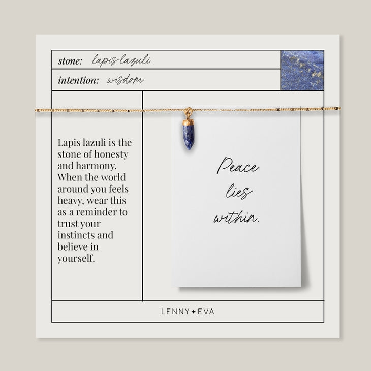 The jewelry packaging features a handcrafted Spike Lapis gold necklace from Lenny & Eva, complete with a card that reads "Peace lies within." Known for its wisdom-enhancing properties, this exquisite piece embodies the harmony and honesty linked to genuine gemstones.