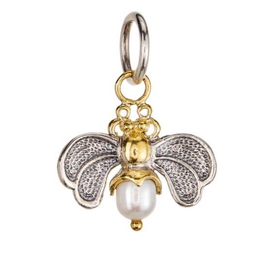 The Crystal Honeypearl Bee Charm by Waxing Poetic features sterling silver wings, a gold-toned body, and a freshwater pearl as the bee’s lower part, attached to a circular metal loop.
