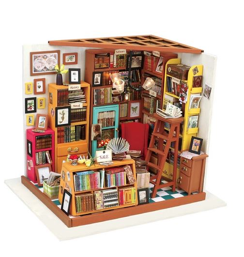 The Sam’s Study Room DIY Miniature Kit by Hands Craft is a colorful 3D wood puzzle featuring bookshelves, ladders, tiny books, and a sales counter—creating a cozy, vibrant mini-study room scene.