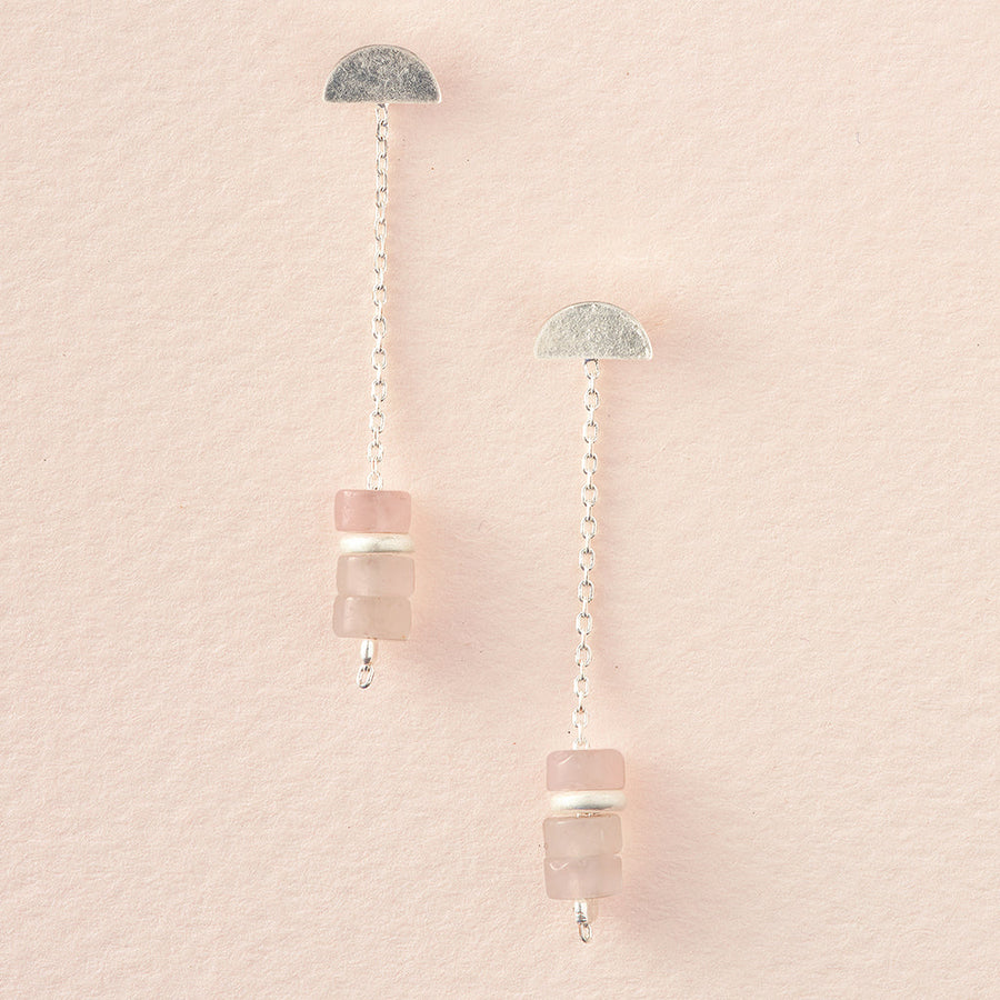 The Meteor Thread Rose Quartz Silver earrings by Scout Jewelry feature sterling silver with half-circle studs, delicate chains, and stacked pale pink and white beads; hypoallergenic, nickel- and cadmium-free—shown on a soft pink textured background.
