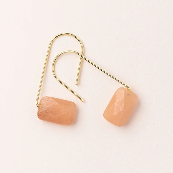 Scout Jewelry's Floating Earring Sunstone/Gold features thin gold hooks and rectangular peach-colored sunstone pendants, displayed on a light background.
