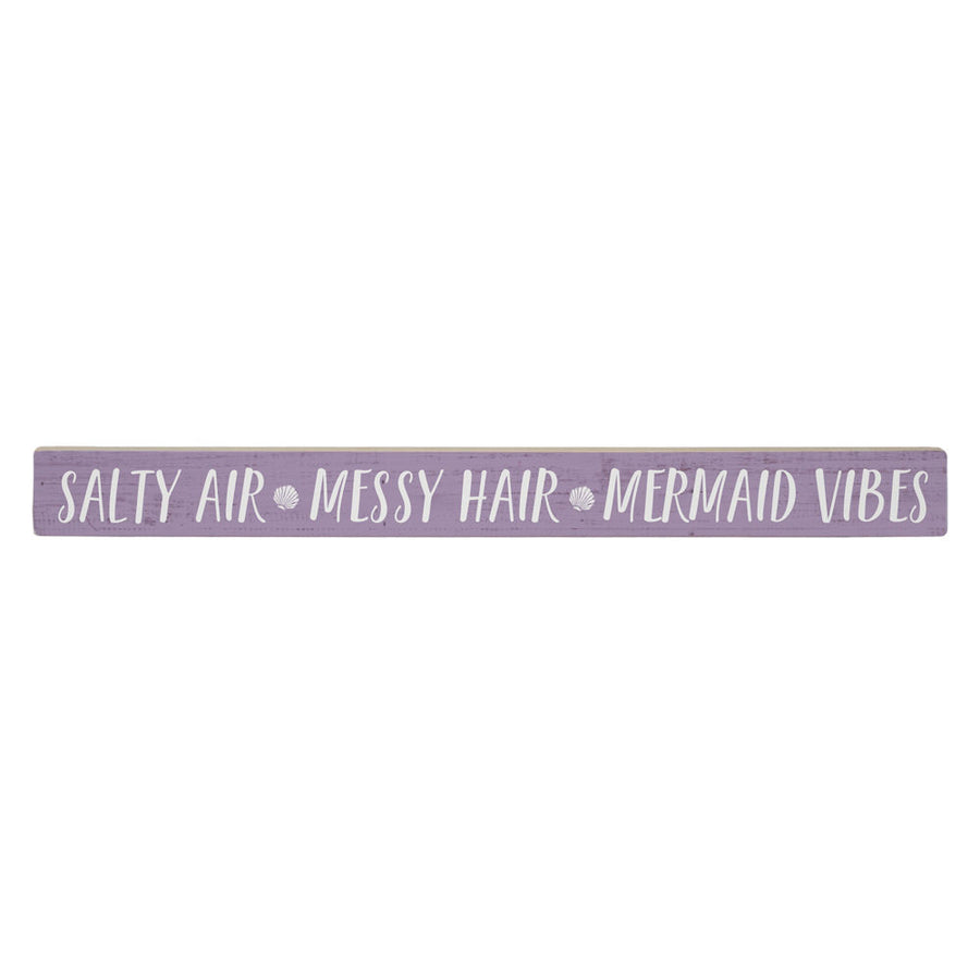A long, handcrafted purple wooden SincereSurroundings Salty Air sign features "SALTY AIR • MESSY HAIR • MERMAID VIBES" with shell icons between phrases. Complements any wood shelf with its white finish.