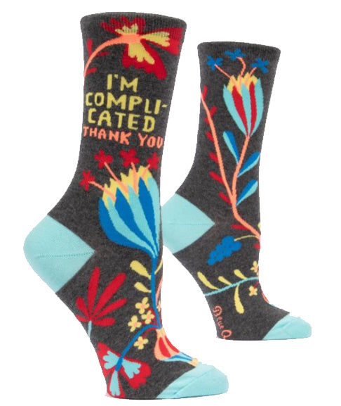 Blue Q's Im Complicated Socks are gray women's socks with colorful floral patterns, light blue heel and toe, and "I'M COMPLICATED THANK YOU" in bold multicolored letters. Made from soft combed cotton.