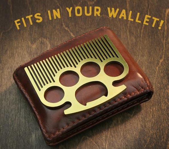 A pocket-sized, stainless steel Brass Knuckle Pocket Comb by LuckyJack rests on a brown leather wallet. Bold yellow text above reads, "FITS IN YOUR WALLET!" The background features a wooden surface.