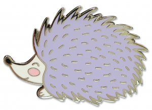 The **Hedgehog Pin** by **PeterPauperP** is an adorable, stylized hard enamel pin featuring a hedgehog with a lavender-colored body, small pink cheeks, and a slightly smiling face. The edges are outlined in metallic gold, adding a shiny appearance. Perfect for adding charm to your jacket or bag, it comes packaged in a delightful gift box.